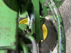 Zbliżenie na wyciek oleju hydraulicznego na zielonej części maszyny John Deere, widoczny nalot oleju i przylegające przewody.