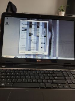 Ekran laptopa Dell z widocznymi zakłóceniami i czarno-białym obrazem.