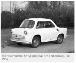 Czarno-białe zdjęcie mikrosamochodu Smyk z 1957 roku z dwoma osobami w środku.