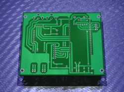 Bottom side of green PCB showing traces and mounting holes for components.