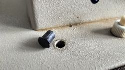 Plastikowa zaślepka i otwór na maszynie do szycia bez gałki do opuszczania transportera.