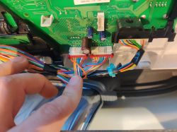 Osoba dotyka kolorowego okablowania podłączonego do płytki drukowanej urządzenia elektronicznego.