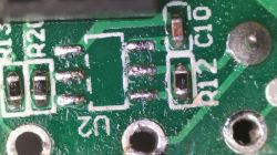 Close-up of a PCB with missing IC chip, exposed solder pads, and nearby SMD resistors