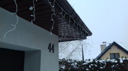Lampki LED zamontowane pod dachem budynku, z których ostatnie 10 sopli nie świeci.