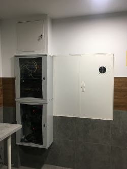 Cabinet with control modules and wiring on a workshop wall.