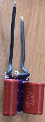 Close-up of a small electronic board with two red CBB22 capacitors rated at 400V.