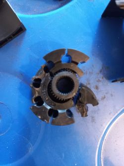 Zużyty mechanizm przenoszący napęd z rolki na łańcuch leży na niebieskim tle.