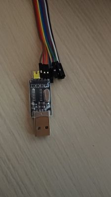 USB-UART converter with attached colored wires on a table.