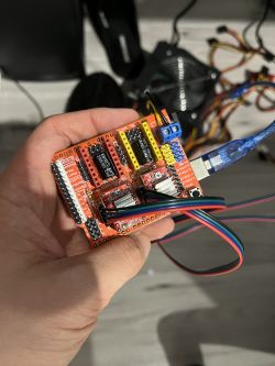 Osoba trzymająca tarczę CNC podłączoną do Arduino Uno z podłączonymi przewodami i sterownikami silników krokowych.