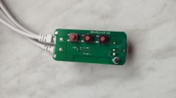 Zielona płytka PCB z trzema czerwonymi przyciskami, opisem AM+MIC+IR-V2 i dwoma białymi przewodami.