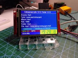 LCD module on a work mat shows an MP3 player screen with track metadata and a clock reading 19:28:18.