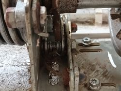 Zbliżenie na mechanizm bramy garażowej z widocznymi zębatkami i sprężynami.