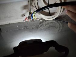 Zbliżenie na kable elektryczne z gołymi końcówkami pod meblami.