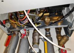 Interior of a heating device with visible pipes, valves, and wiring.