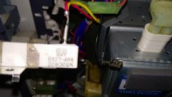 Biały rezystor RX27-4HA 20W 300ΩK z podłączonym przewodem wśród kolorowych kabli
