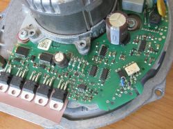 Zbliżenie zielonej płytki PCB z elementami elektronicznymi i dużą cewką w metalowej obudowie