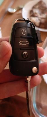 Kluczyk do samochodu z trzema przyciskami, trzymany w dłoni.