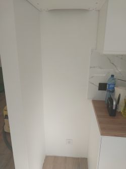 Wnęka w kuchni przeznaczona na lodówkę z białymi ścianami i gniazdkiem elektrycznym.