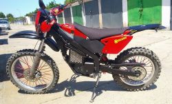 Red off-road motorcycle parked outside near a row of garages.