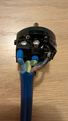 Wtyczka z przewodem i śladami przegrzania przy zaciskach oraz stopionym plastikiem po prawej.