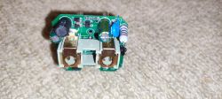 Interior of an Electronic Device with Visible PCB Photo of an open electronic device showing the PCB and components on a carpet.
