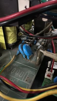 Zbliżenie na płytę elektroniczną z widocznymi niebieskimi kondensatorami i przewodami.