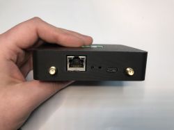 Osoba trzyma czarne urządzenie z portem Ethernet, USB-C i dwoma złączami antenowymi SMA.