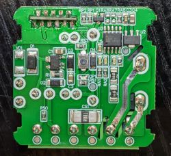 Close-up of a green PCB with electronic components and a cut trace at the top.