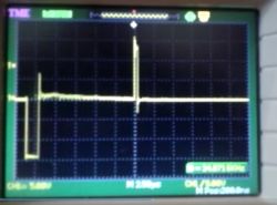 Wykres z oscyloskopu pokazujący sygnał z dodatnimi i ujemnymi impulsami na ekranie.
