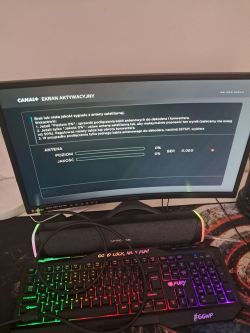 Monitor MSI wyświetlający ekran aktywacyjny CANAL+ z informacją o braku sygnału satelitarnego, poniżej kolorowa klawiatura gamingowa FURY i soundbar Gaming Trust.