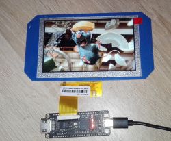 Wyświetlacz LCD IPS 800x480 z podłączonym Tang Nano 9K, wyświetlający obraz animowanej postaci.