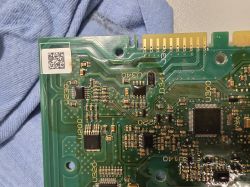 Section of a green printed circuit board with electronic components and a QR code sticker.
