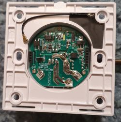 PCB mounted in white wall casing with electronic components and black antenna