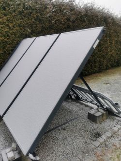 Zamontowane panele solarne pokryte szronem, widok z boku na ramę i przyłącza