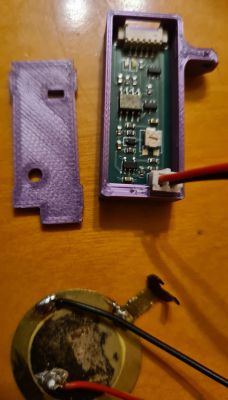 Open purple enclosure with a PCB and wires on a wooden surface