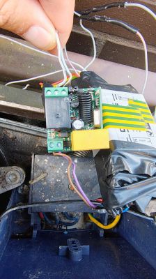 Small black relay with three terminals on a green circuit board, shown in close-up.
