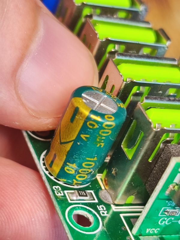 Zbliżenie na kondensator elektrolityczny 10V 1000µF zamontowany na płytce PCB obok portów USB.