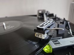 Zbliżenie na gramofon Dual 491 z igłą na obracającej się płycie winylowej.