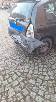 Zdjęcie uszkodzonego tyłu czarnego samochodu po kolizji.