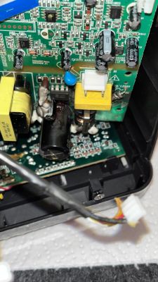 Beschädigter Kondensator auf einer Leiterplatte mit weiteren elektronischen Bauteilen.