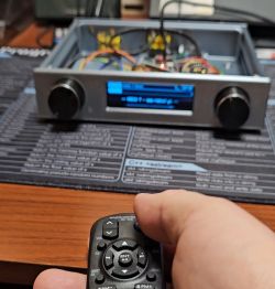 Hand holding RC-406 remote pointing at audio device with display