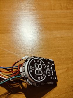 Sterownik z wyświetlaczem cyfrowym i przewodami, umieszczony na drewnianej powierzchni.