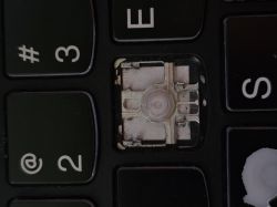Brakujący klawisz „W” na czarnej klawiaturze laptopa, widoczne elementy mechanizmu pod klawiszem.