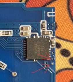 Close-up of a circuit board with red arrows indicating solder points.