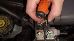 Osoba trzymająca śrubokręt przy bezpieczniku samochodowym