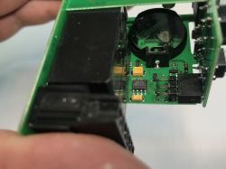 Fragment płytki drukowanej z elektroniką, w tym baterią CR2032 i różnymi komponentami SMD.