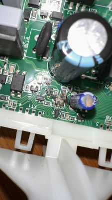 Zbliżenie na płytkę drukowaną z widocznymi śladami przypalenia w pobliżu elementów elektronicznych.