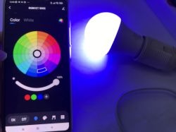 Controlling LED lamp with Tuya app Tuya app on phone next to a glowing LED lamp