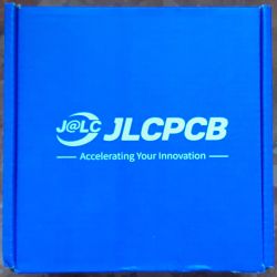 Niebieskie pudełko z białym logo JLCPCB oraz napisem Accelerating Your Innovation.