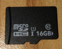 Czarna karta microSDHC 16 GB z oznaczeniem klasy 10 na drewnianym tle